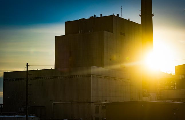 sun setting on an old power plant in the midwest