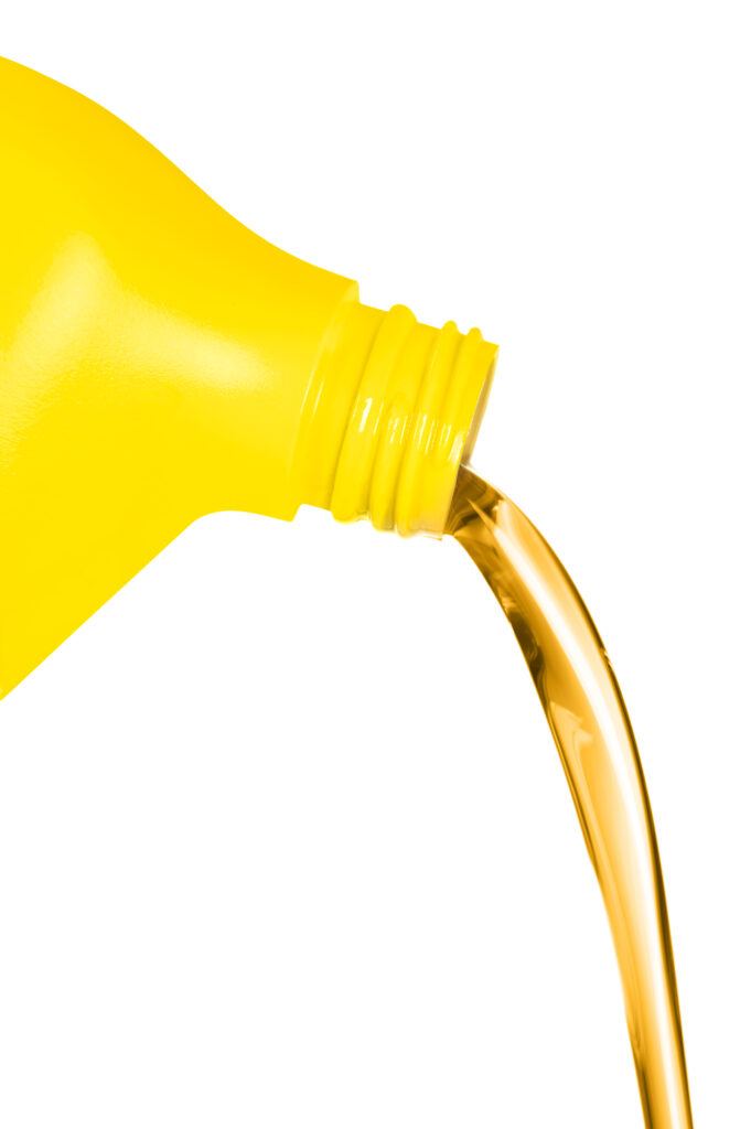A plastic container of engine oil pouring in front of a white background. For use as a design element or automobile maintenance inference